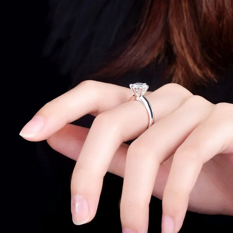 White gold plated six-claw zircon women's ring with geometric shape on a finger.