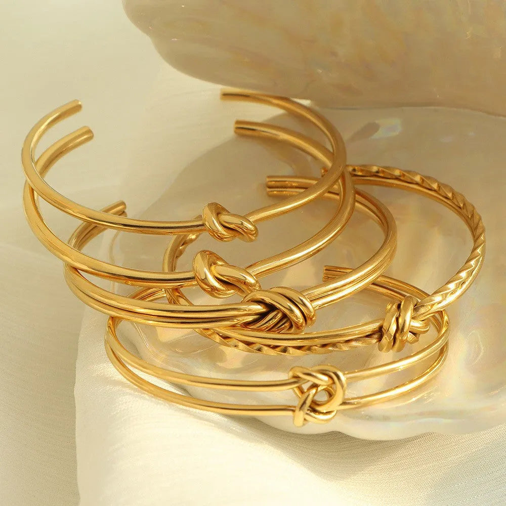 Women's open C-shape knotted double-layer bracelet in gold or silver plating on a wrist.