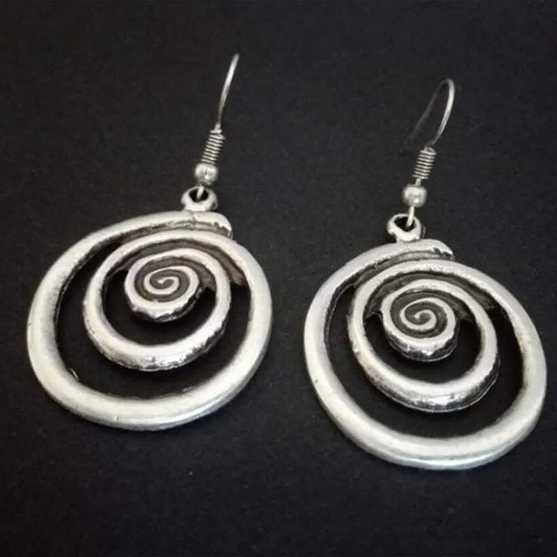 Geometric spiral distressed silver alloy drop earrings on a white background.