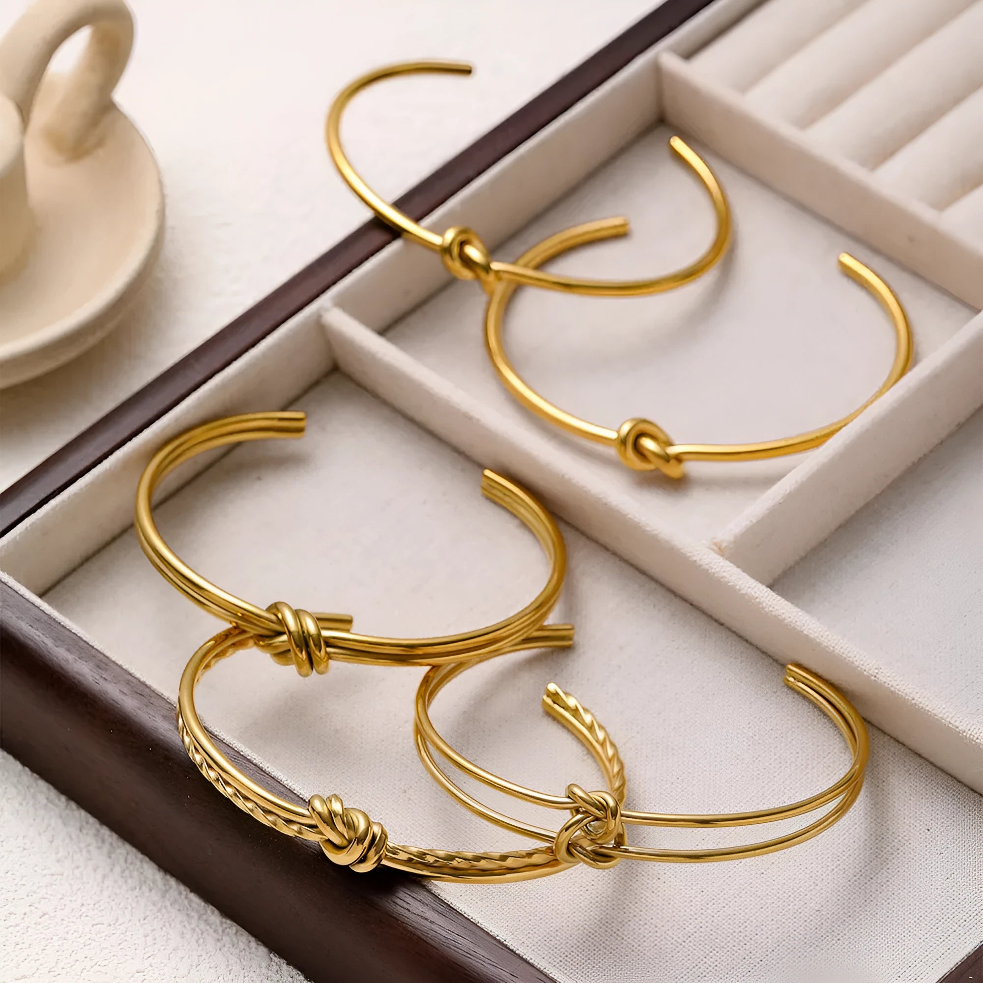 Women's open C-shape knotted double-layer bracelet in gold or silver plating on a wrist.