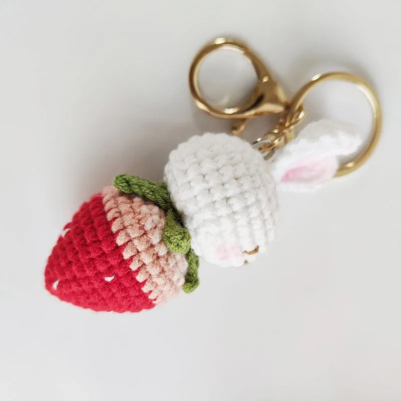 Hand-woven white wire pendant with rabbit and strawberry cartoon pattern, shown with a key attachment.