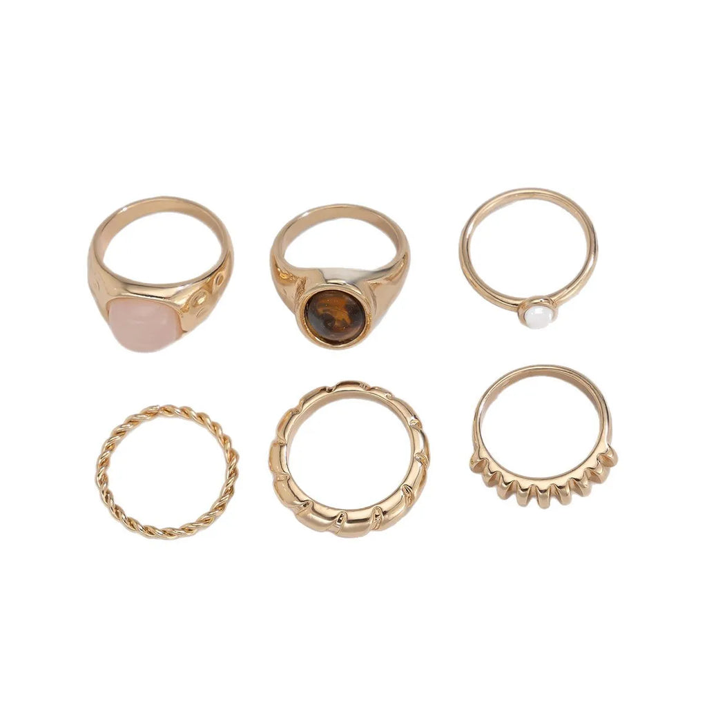 Six light gold alloy rings with geometric shapes and round elements arranged as a complete ring suit
