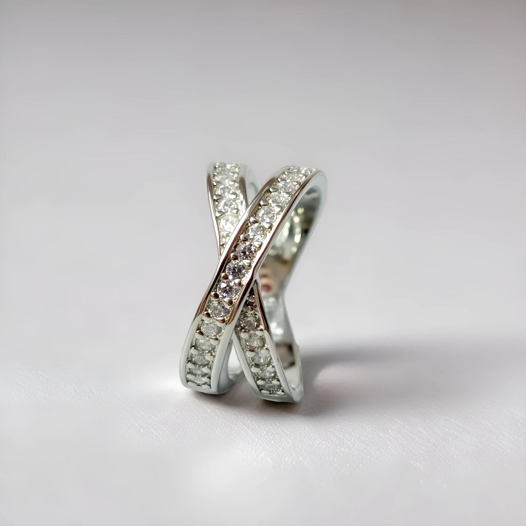Simple metal cross ring with micro-inlaid zircon on a geometric band, shown in silver and rose gold finishes.