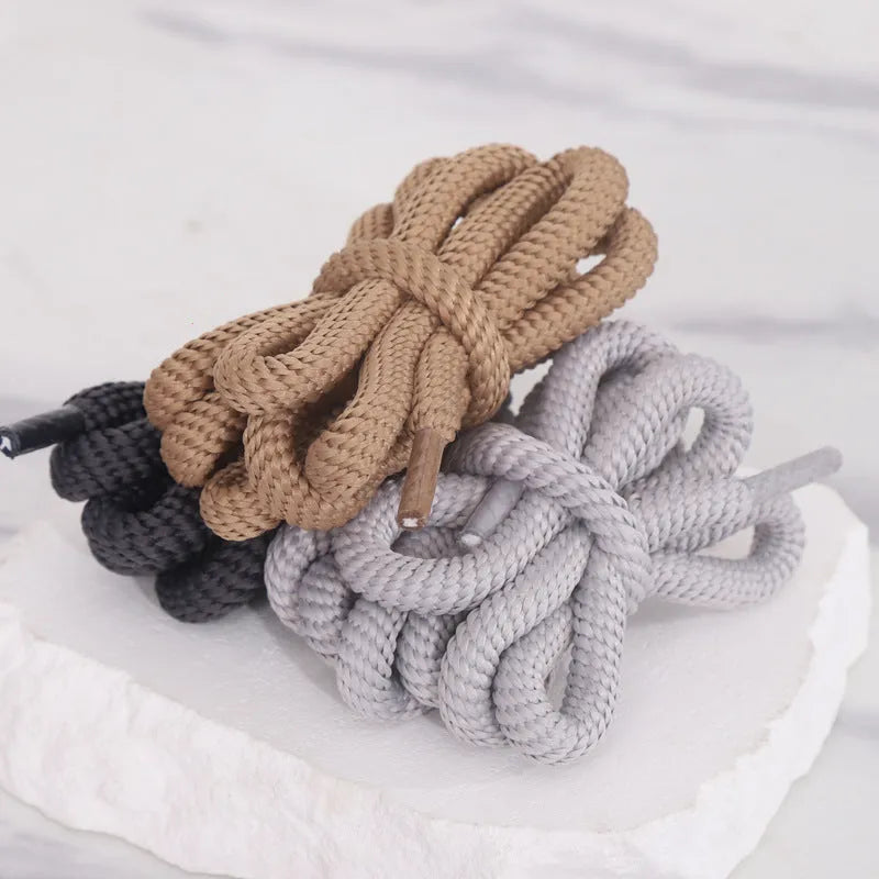 Oval cross-section shoelace adapter rope in various colours, shown next to a trainer and sweatshirt.