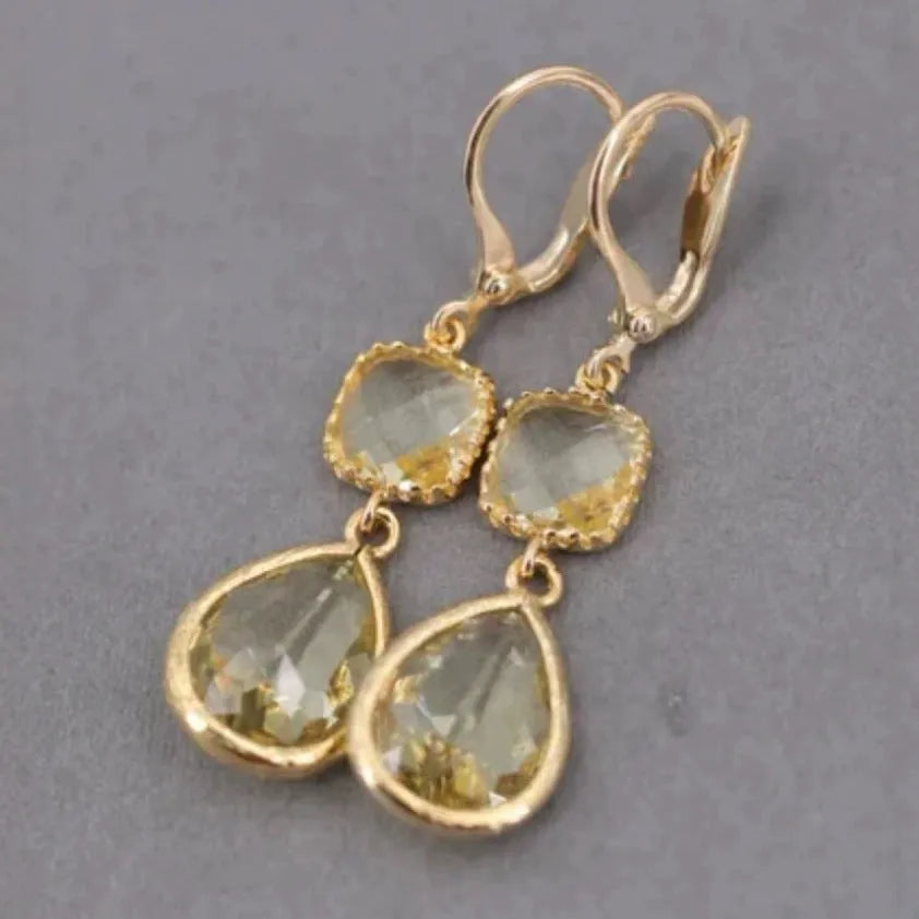 Gold long drop earrings with geometric shape and water droplet crystal fringe on a model.