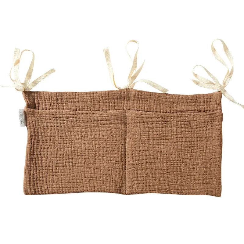 Cotton double layer baby bedside buggy bag in camel colour with tie straps attached to a pram handle