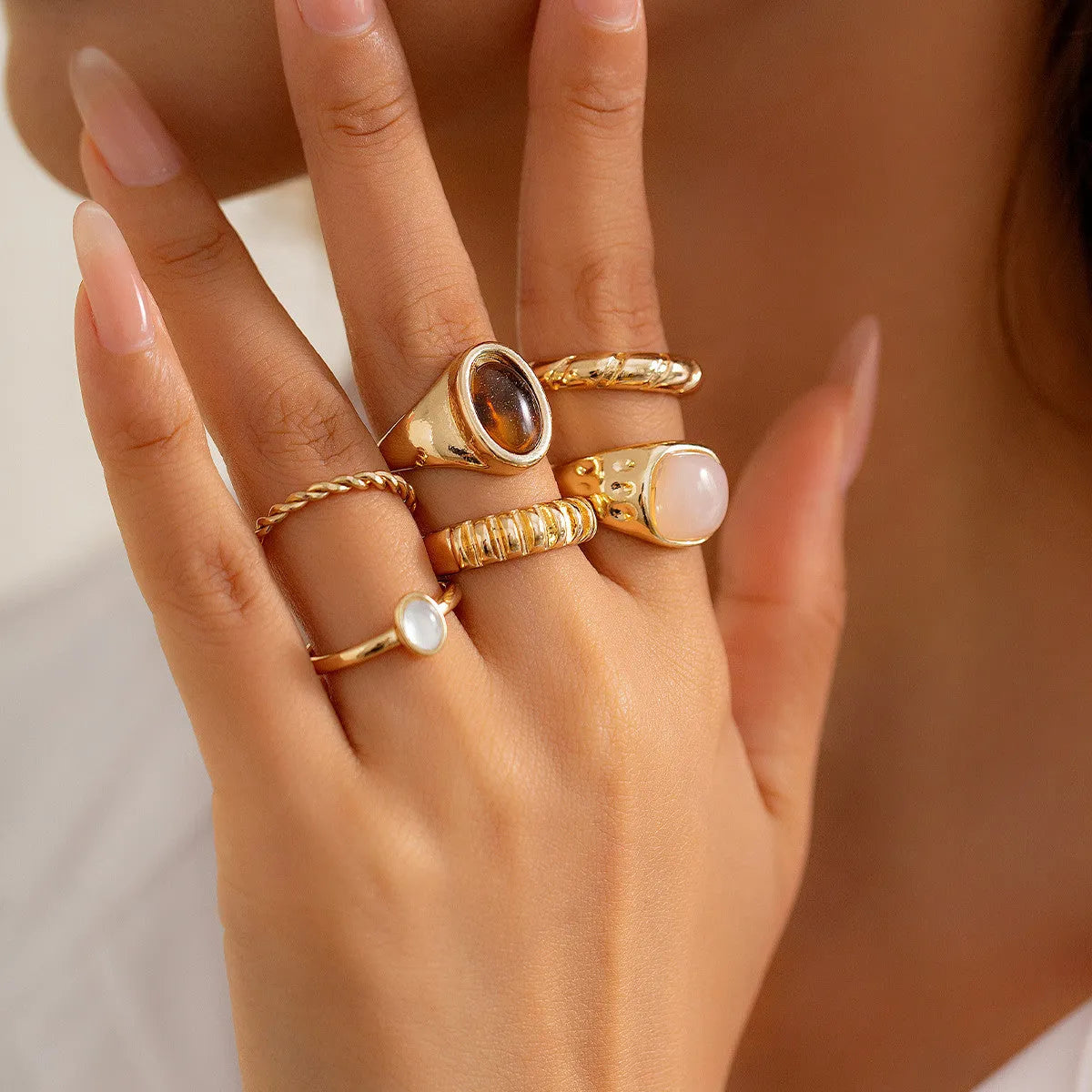 Six light gold alloy rings with geometric shapes and round elements arranged as a complete ring suit