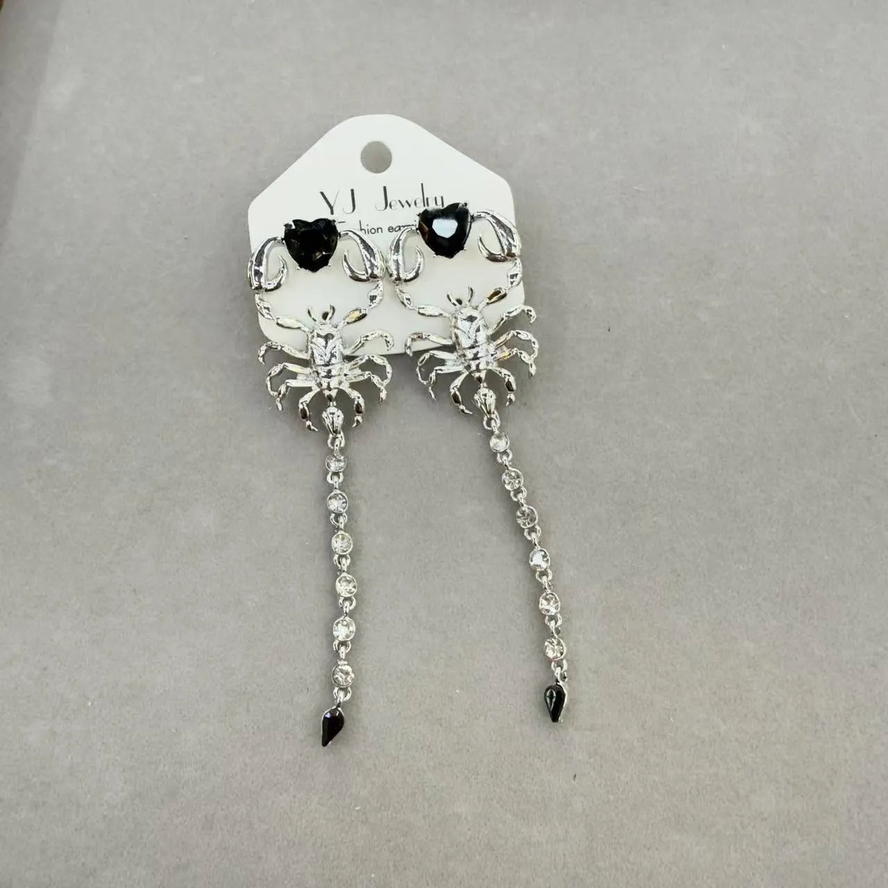 Gold exaggerated insect asymmetric earrings for women on white background with hook fastening