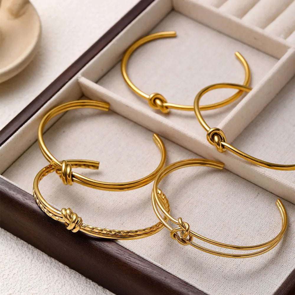 Women's open C-shape knotted double-layer bracelet in gold or silver plating on a wrist.