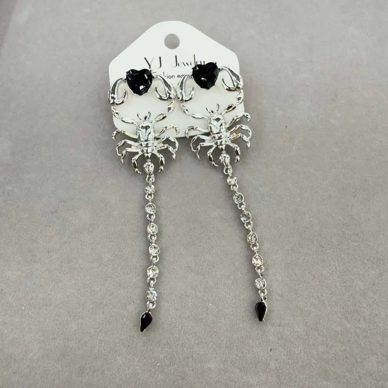 Gold exaggerated insect asymmetric earrings for women on white background with hook fastening