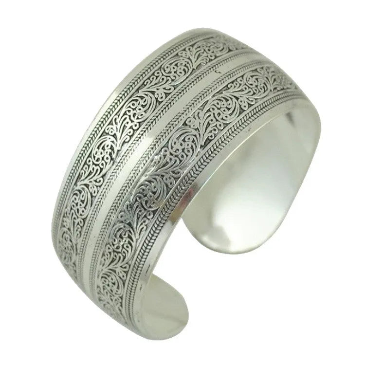 Ethnic style open carved Miao silver alloy bracelet in Roman shape on wrist.