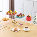 Six identical white plastic cube dessert display stands arranged together.