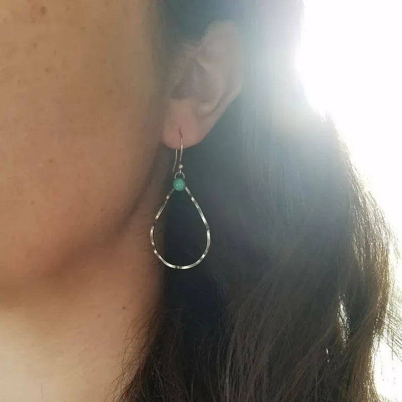 A pair of vintage bohemian style earrings with a turquoise circle design in antique silver.