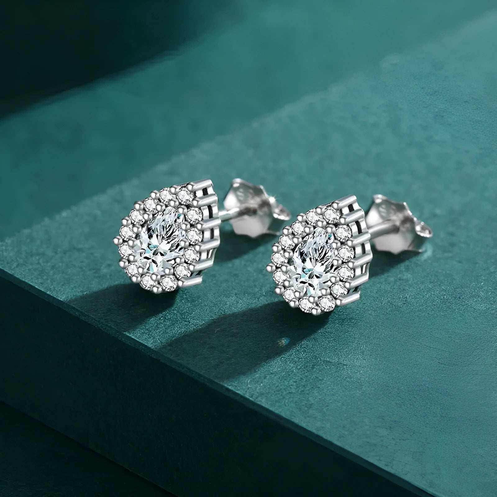 A pair of silver water drop shaped stud earrings with a diamond-cut faceted surface.