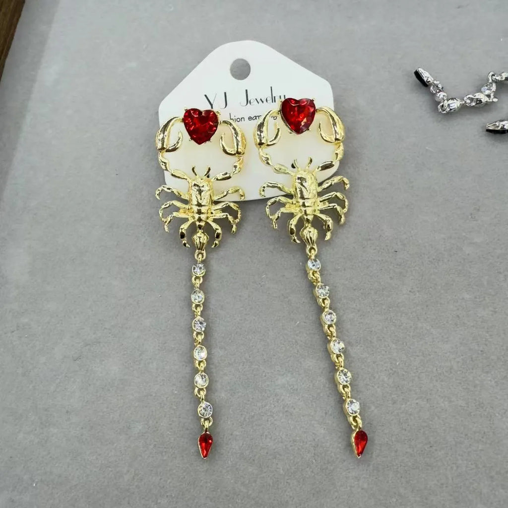 Gold exaggerated insect asymmetric earrings for women on white background with hook fastening