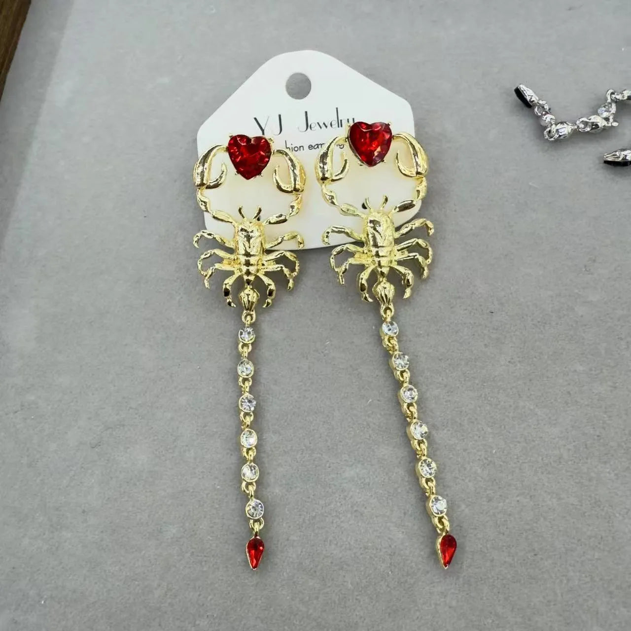 Gold exaggerated insect asymmetric earrings for women on white background with hook fastening