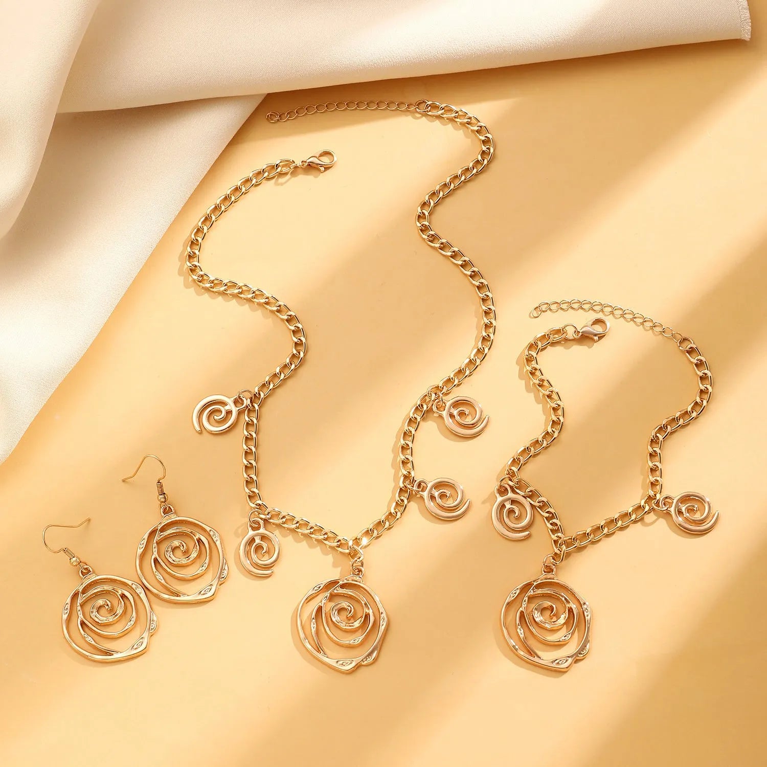 Spiral donut design alloy necklace, bracelet and earrings set in gold or silver electroplated finish.