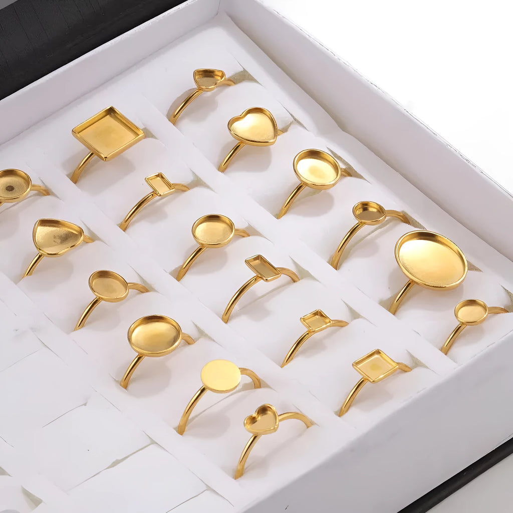 Assortment of golden stainless steel DIY jewellery settings in oval, heart, round, square, and rectangle shapes with totem pattern.