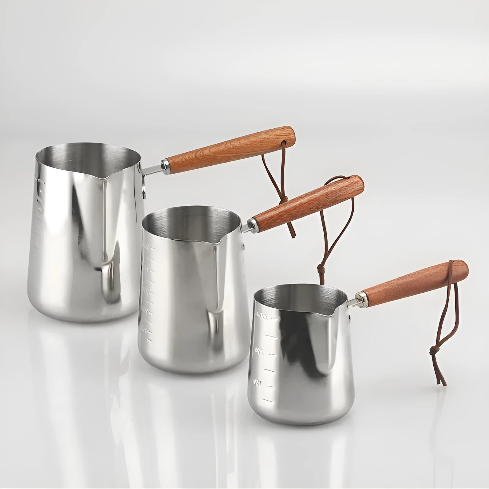 Stainless steel latte art milk cup with wooden handle and visible internal measurement scale.