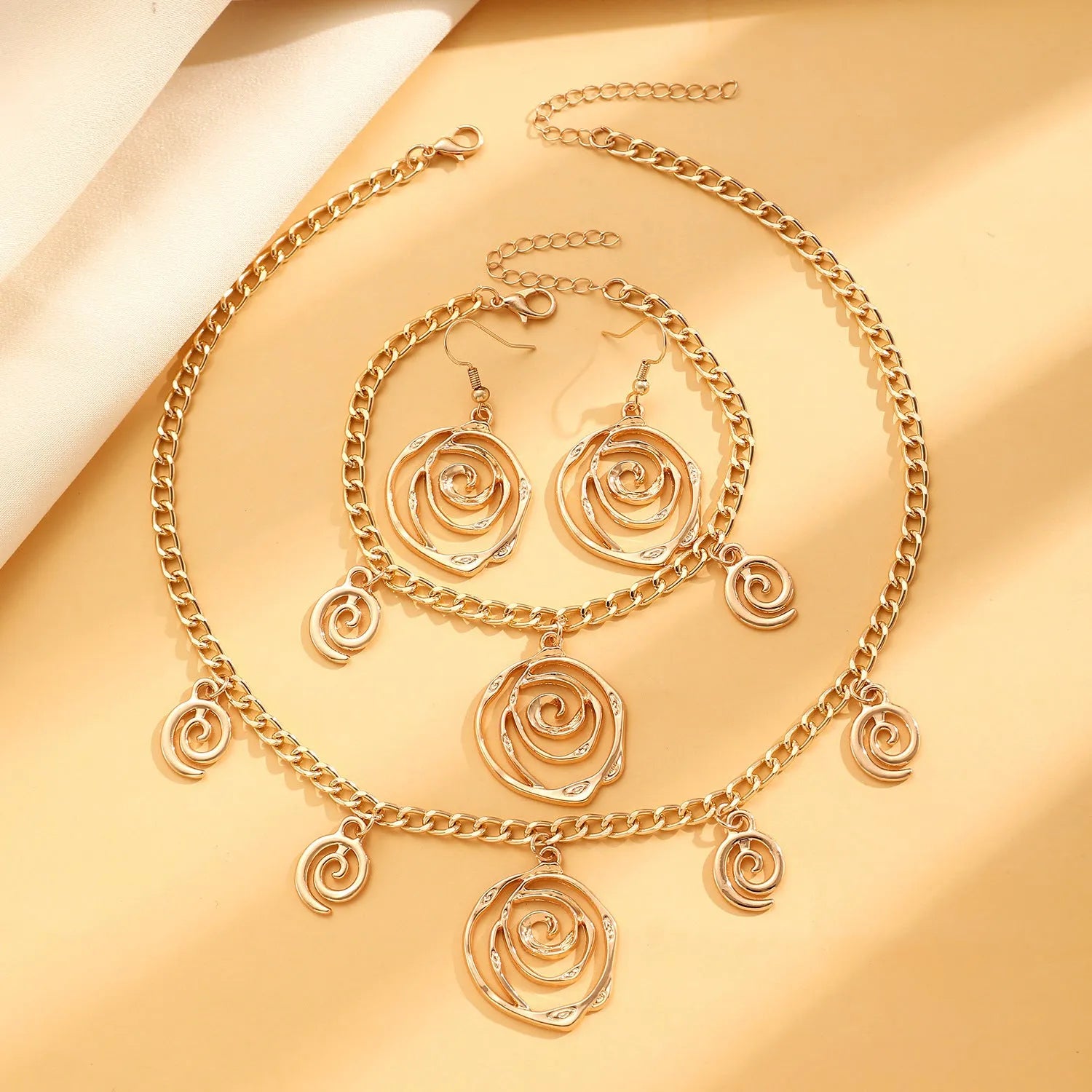 Spiral donut design alloy necklace, bracelet and earrings set in gold or silver electroplated finish.