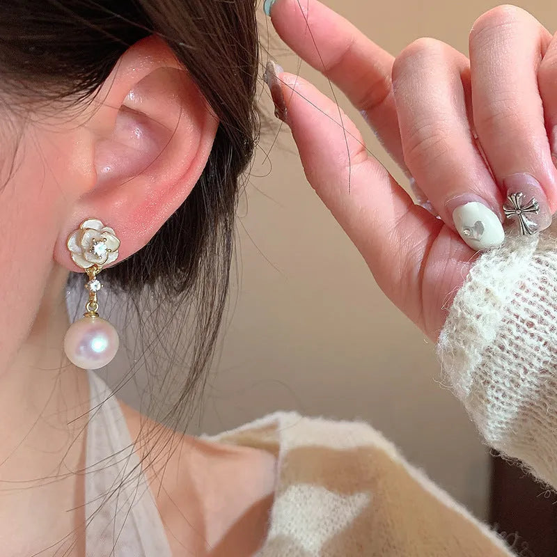 Close-up of Camellia Pearl Flower Stud Earrings for women, showing detailed floral alloy design with faux pearl centre.