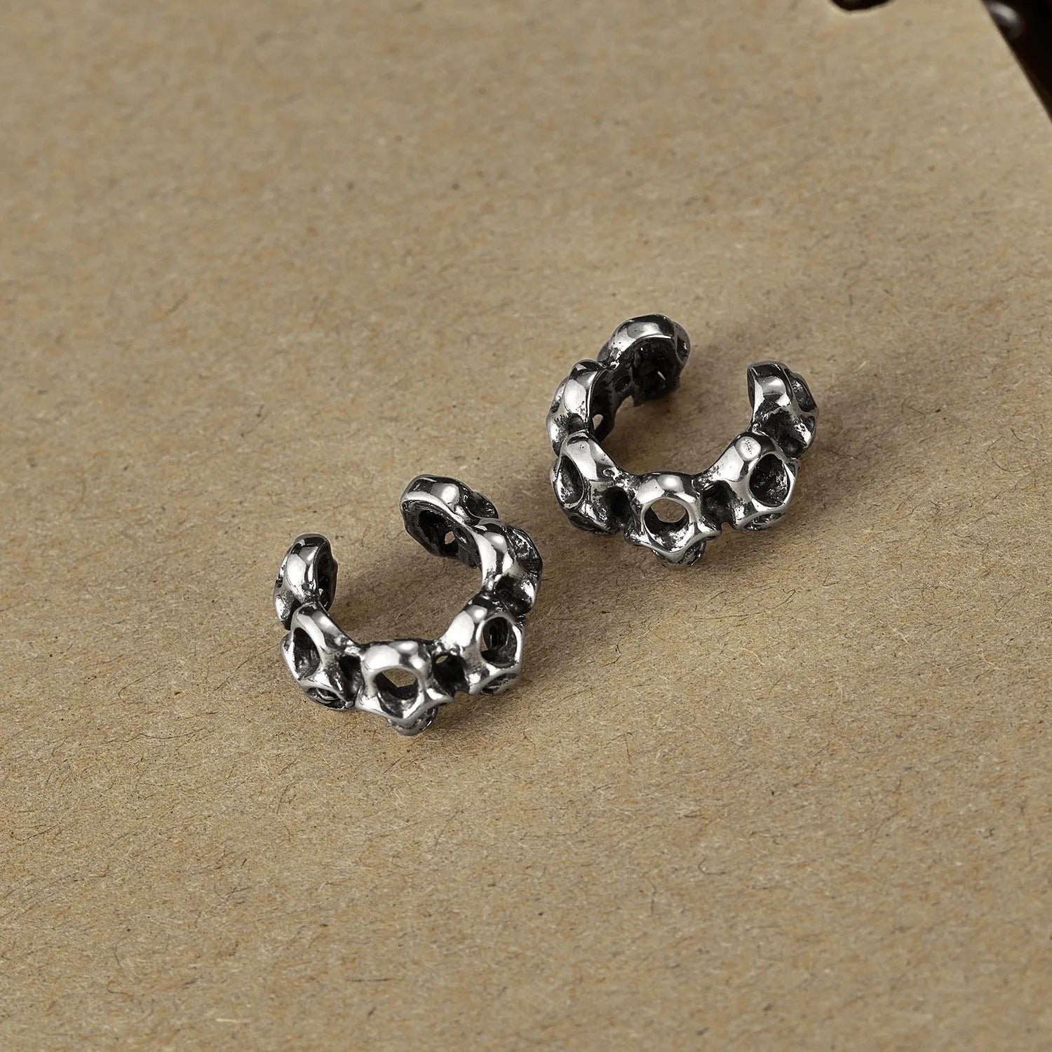 Stainless steel clip-on earrings featuring a hollow geometric skull design with an electroplated finish.