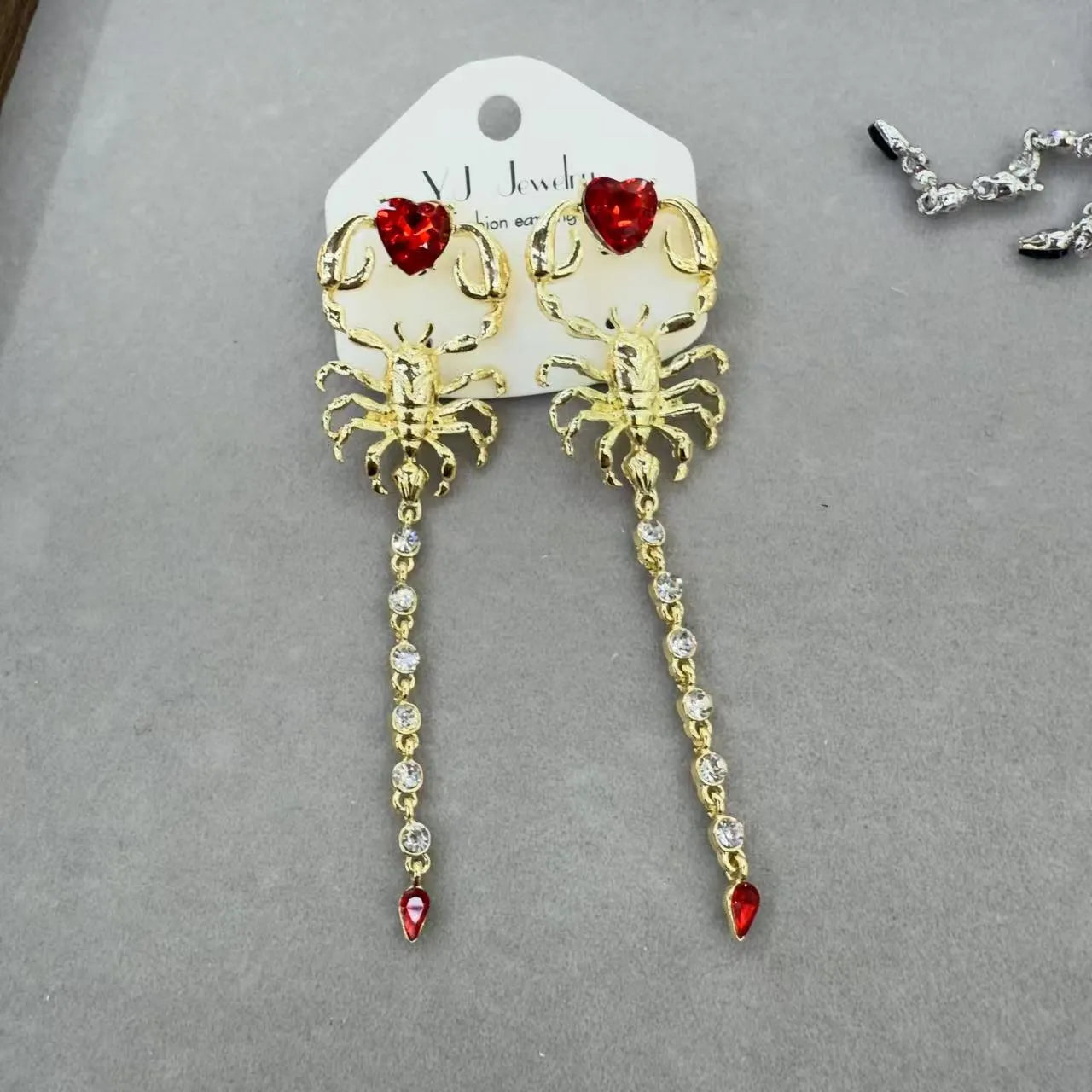 Gold exaggerated insect asymmetric earrings for women on white background with hook fastening