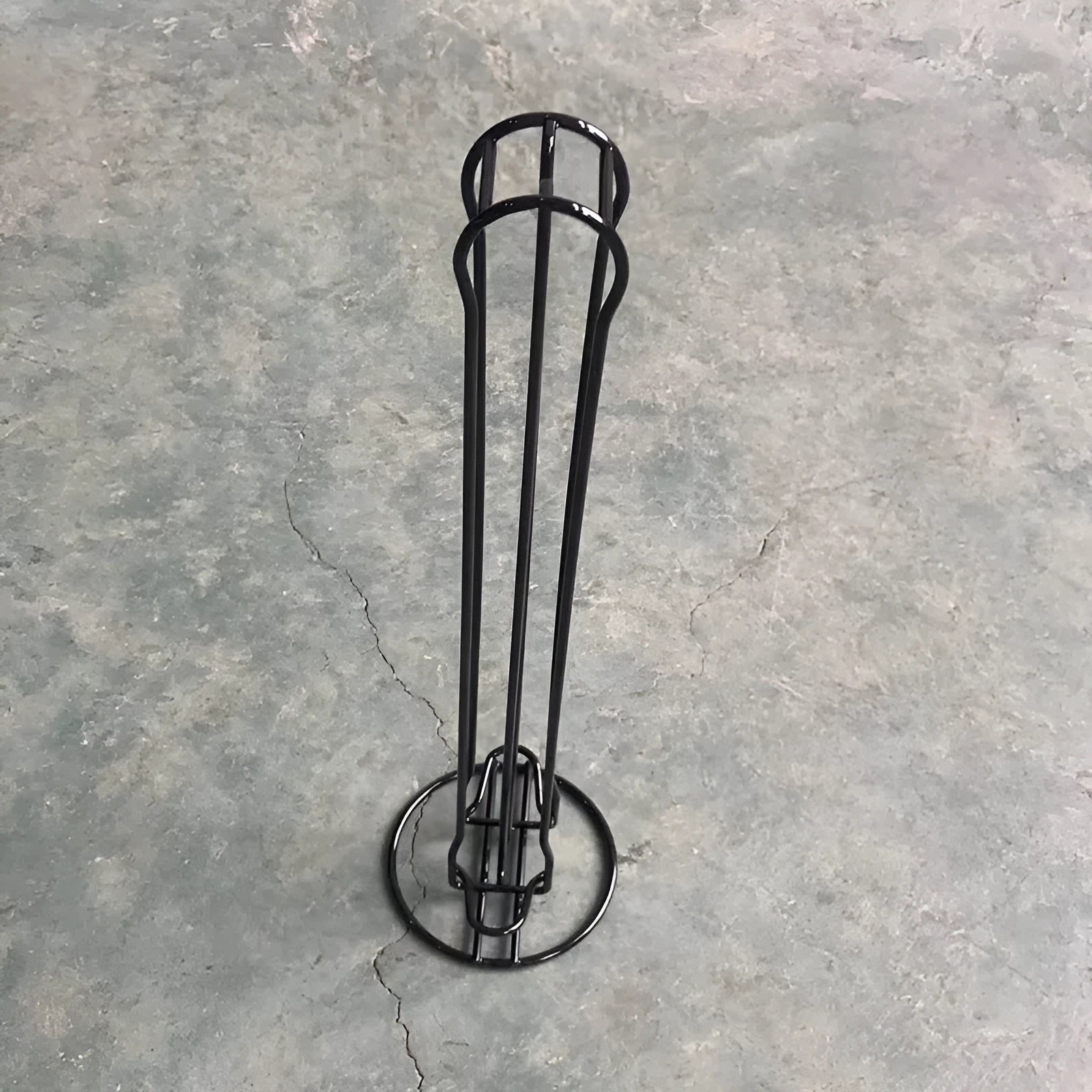 Black wrought iron coffee capsule storage rack holding pods on open shelves