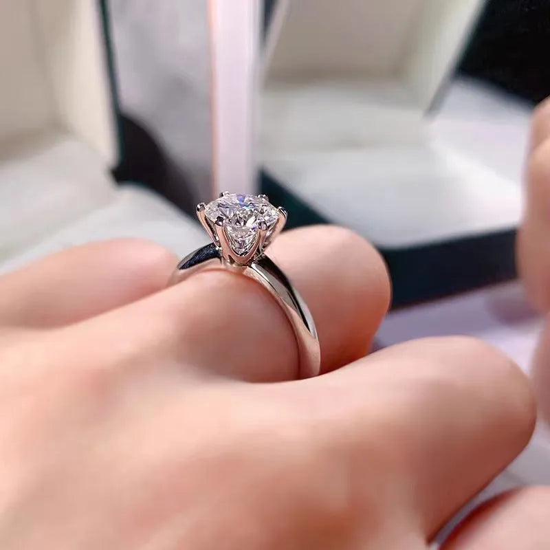 White gold plated six-claw zircon women's ring with geometric shape on a finger.