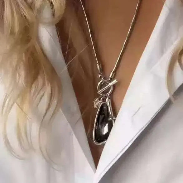 Long geometric alloy pendant necklace with snake bones chain for wearing over sweaters.