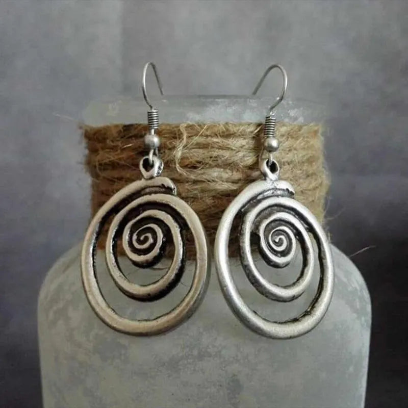 Geometric spiral distressed silver alloy drop earrings on a white background.