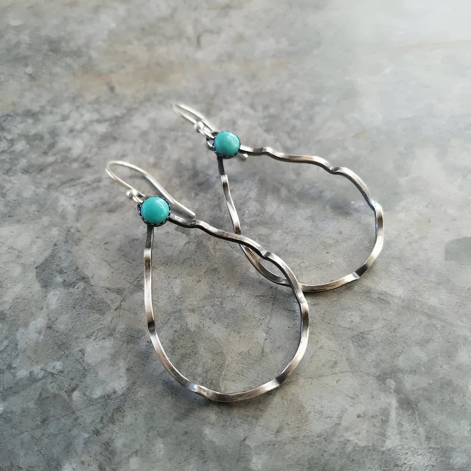 A pair of vintage bohemian style earrings with a turquoise circle design in antique silver.