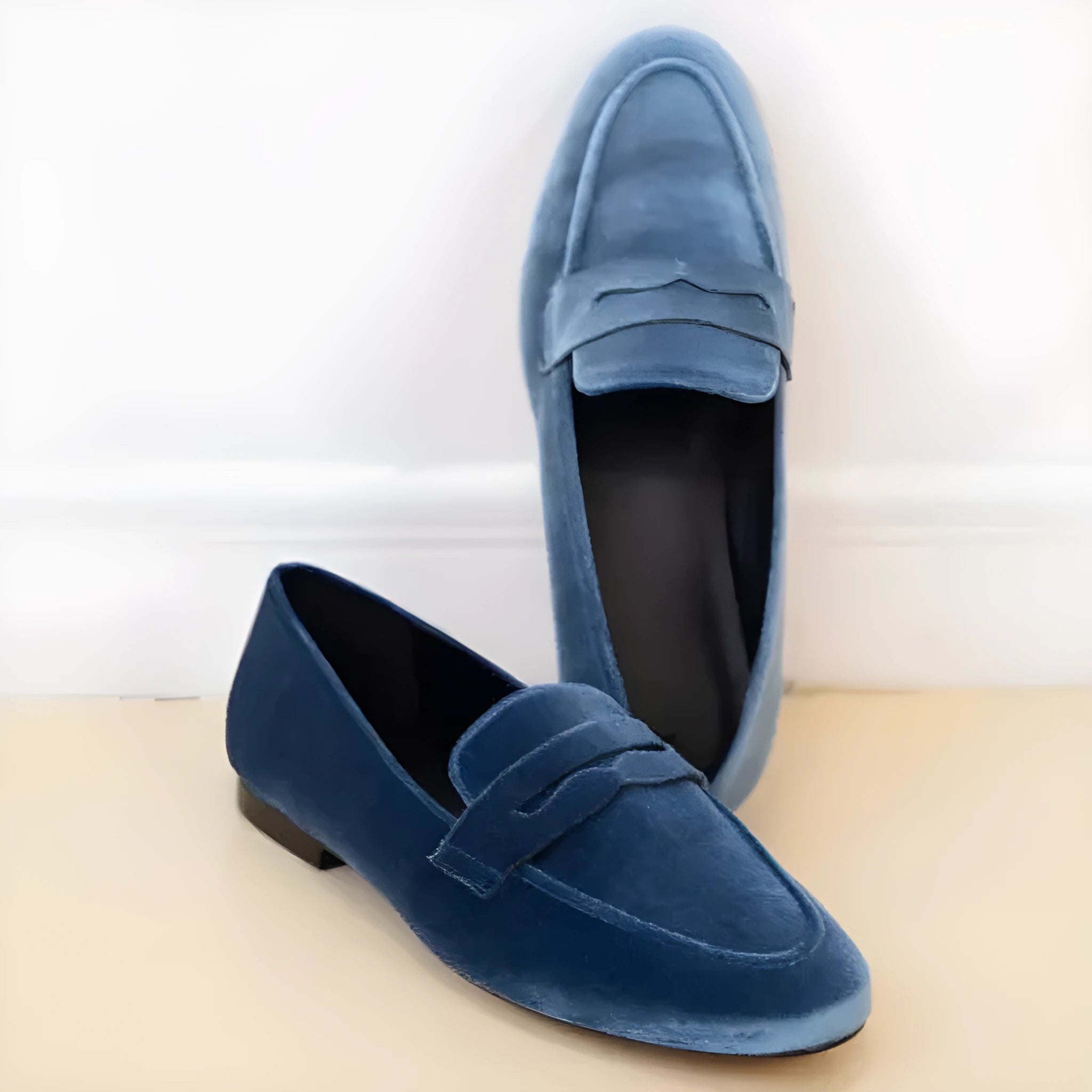 Blue women's flat slip-on loafers with a black rubber sole, shown in a side view.