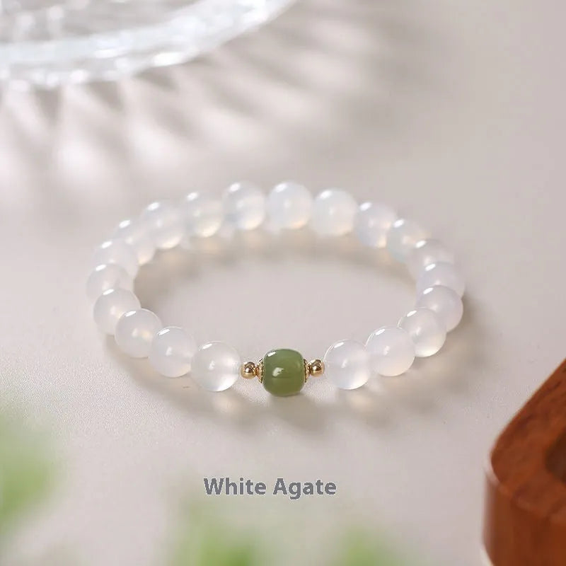 Handmade white agate and cinnabar bracelet with text design on a wrist.