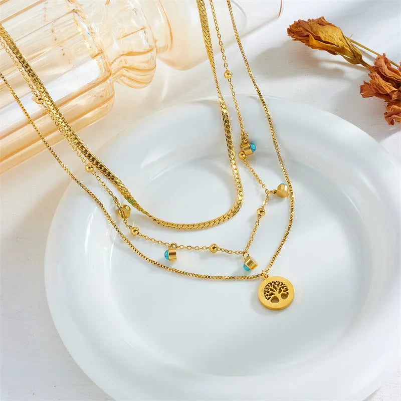 Gold-plated multi-layer stainless steel necklace with geometric tree pendant on woman