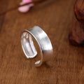 Frosted silver geometric open ring with adjustable sizing on a neutral background
