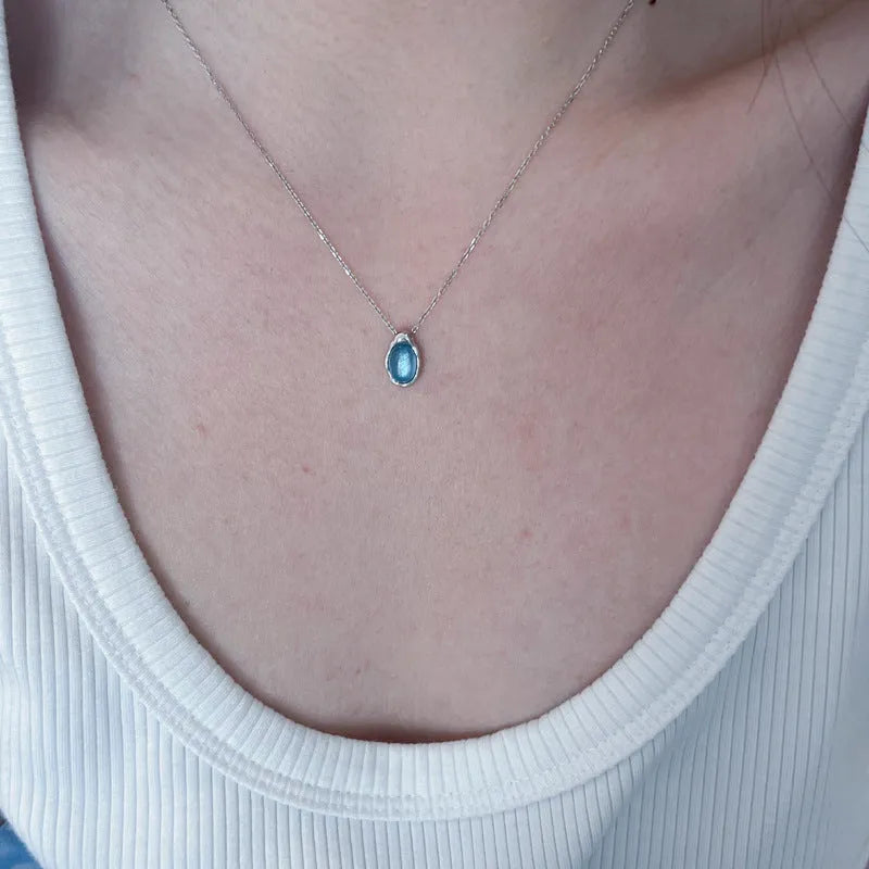 Navy blue water drop geometric pendant necklace with cross chain on white background