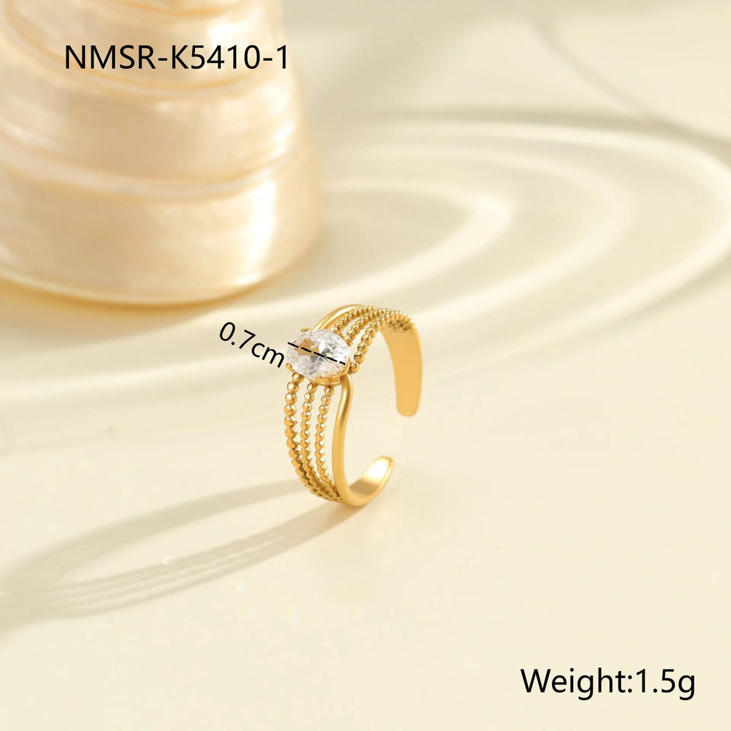 Gold-coloured adjustable stainless steel ring with zircon geometric shapes on white background.