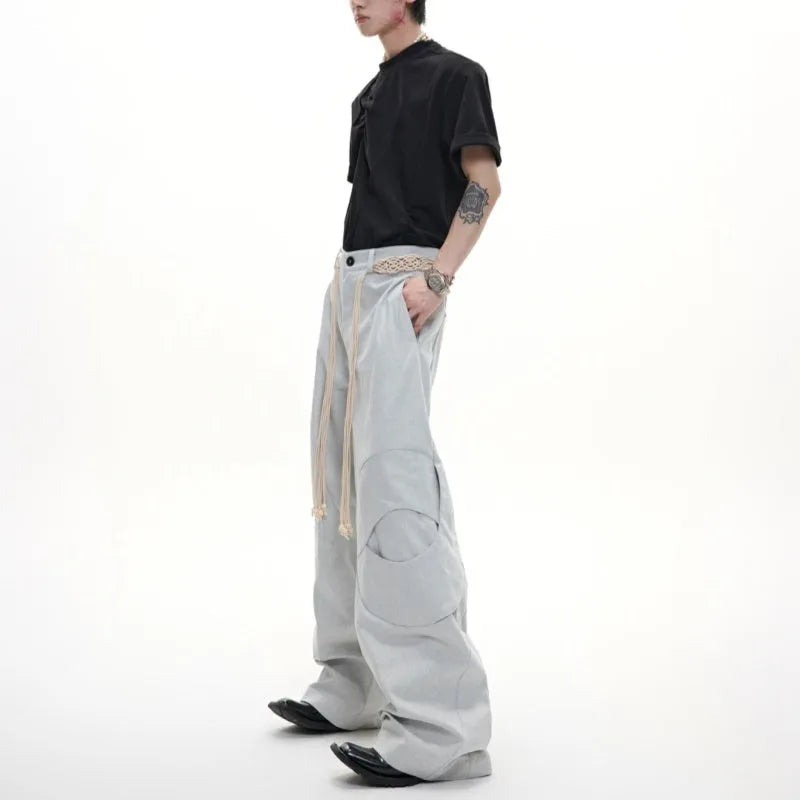 Man wearing dark blue straight-leg cotton jeans with loose fit, zipper decorations, and a tassel detail.