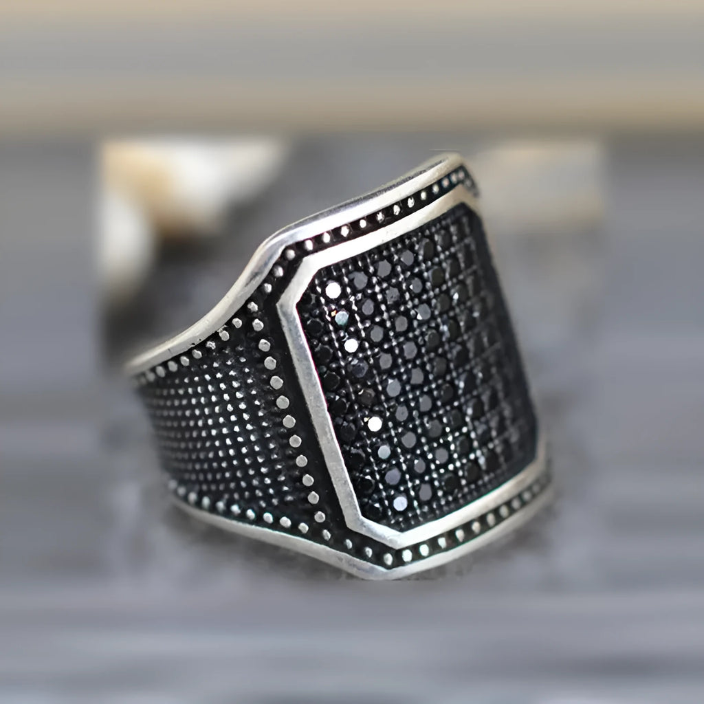 Black alloy ring with a zircon stone and copper inlay detail, shown in a unisex style.
