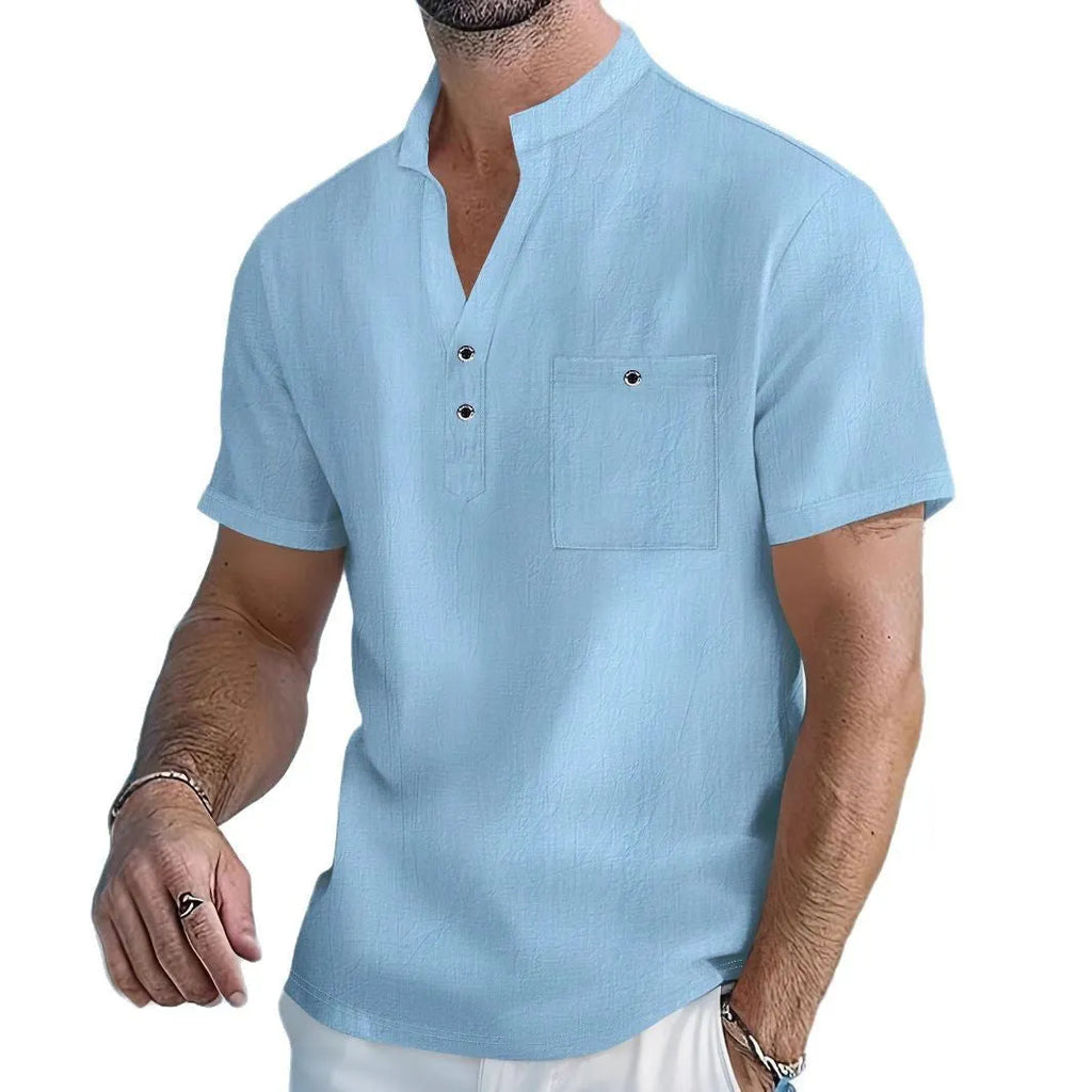 Man wearing a light-coloured, loose fit linen t-shirt with a stand collar and short sleeves.