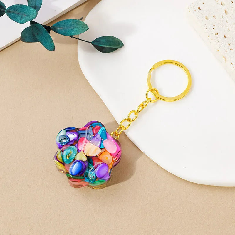 Small natural crystal cat's paw charm on a keyring, showing colour options including pink, red, blue, and purple gemstones.
