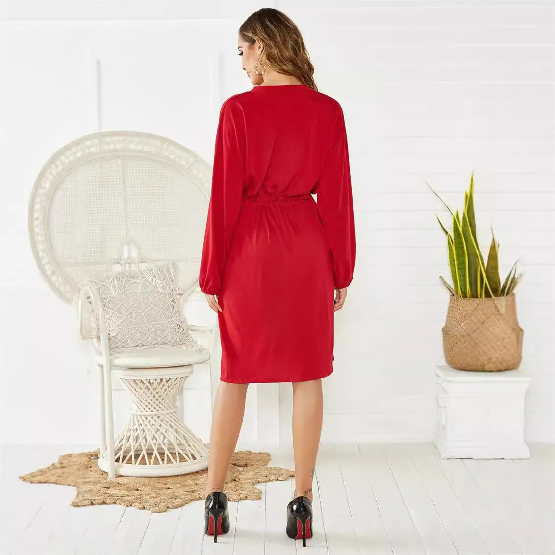 A woman wearing a solid colour A-line midi dress with an elastic waist, an attached belt, and long sleeves.