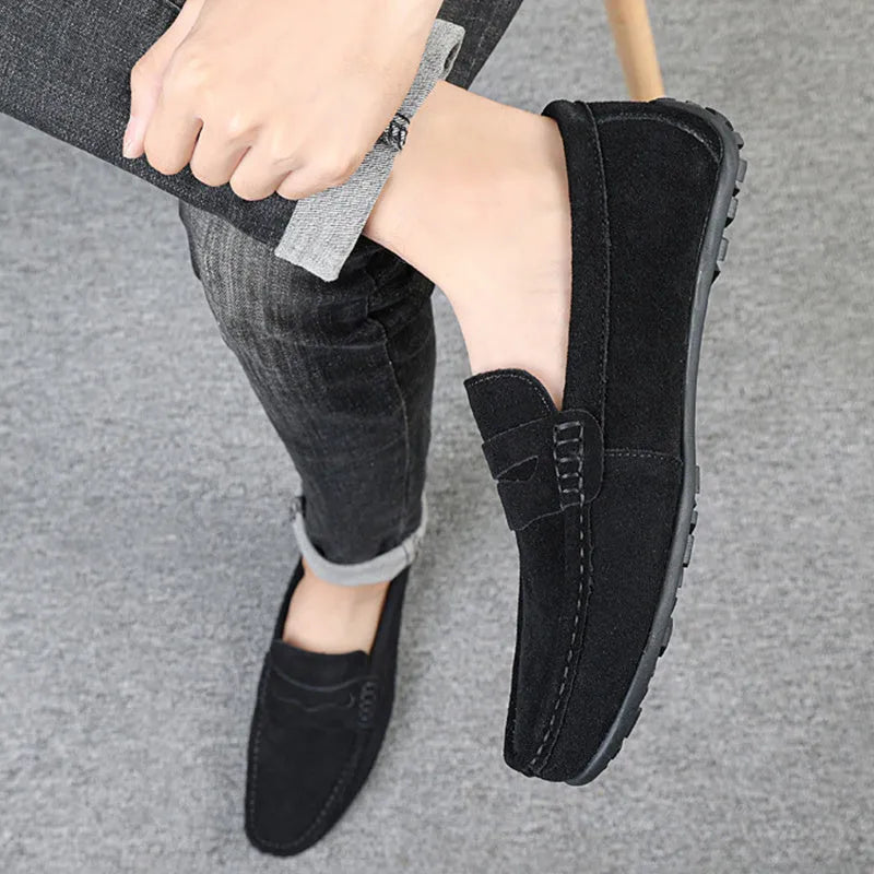 Men's solid colour suede loafers with round toe and rubber sole on a neutral background.