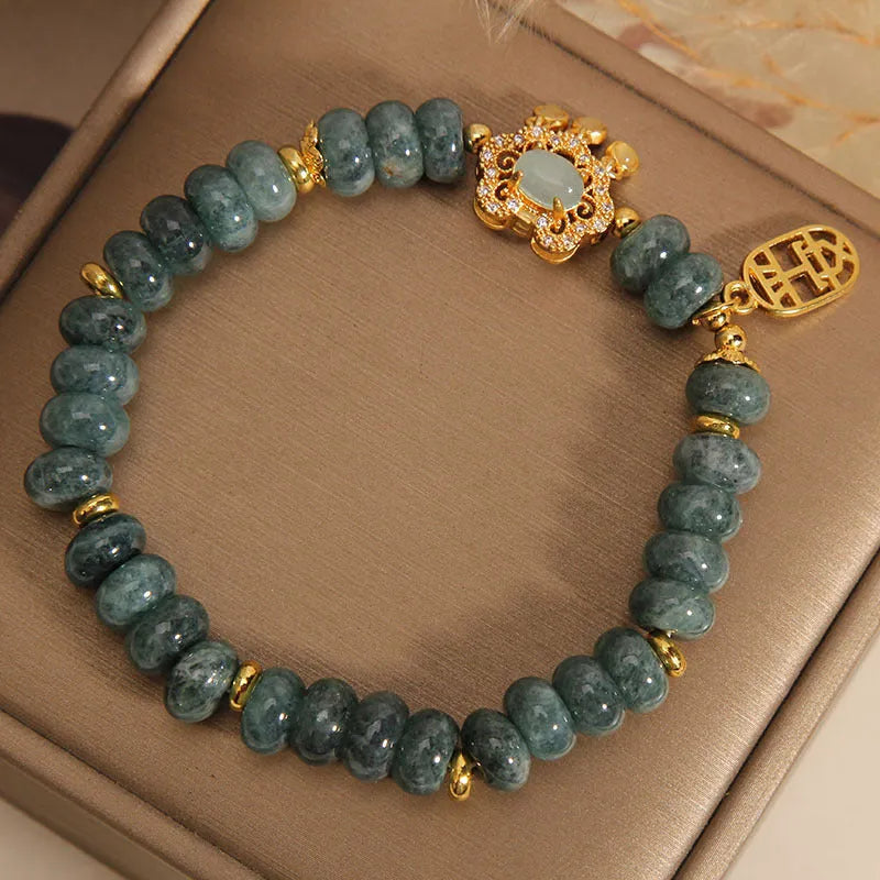Close-up of a women's bracelet with emerald green jade abacus beads and a metallic safety lock clasp.