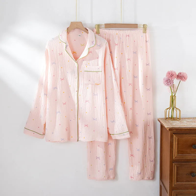 Women's pink cotton long-sleeve pajama top and trousers set laid flat.