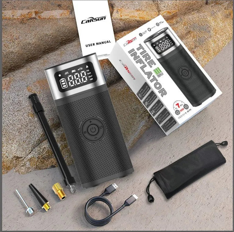 Black portable wireless air pump with USB charging cable, inflation tube, and a set of nozzles on a grey background.