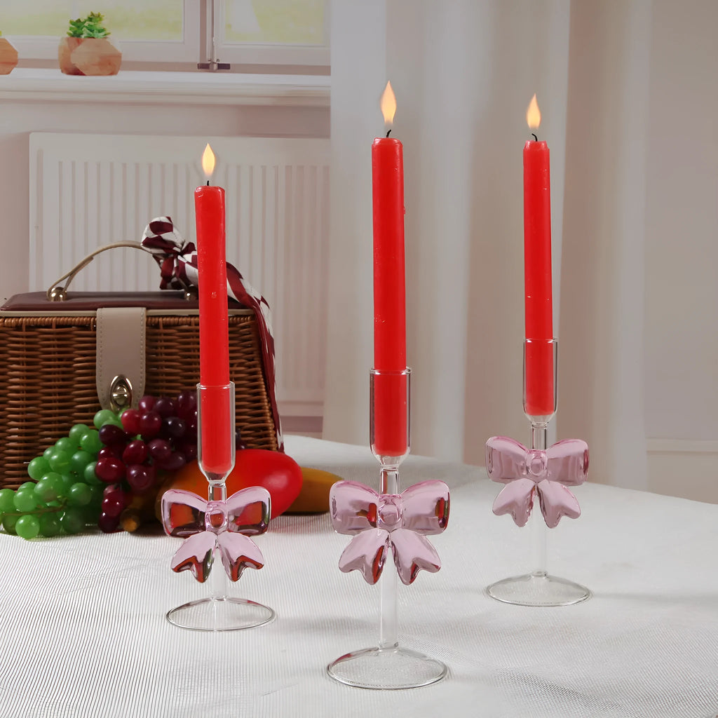 Set of three clear borosilicate glass candlesticks with large bow decorations on a table