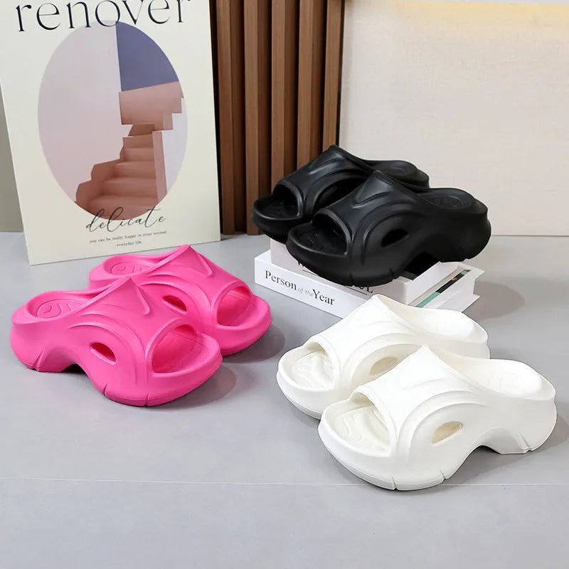Women's thick-soled EVA slippers in rose red colour on a sandy beach.