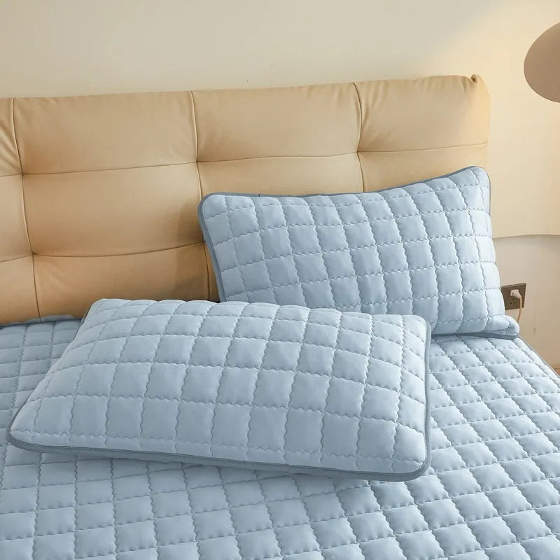 Blue washed cotton fitted sheet with quilted pattern on a bed, showcasing its waterproof protection feature.